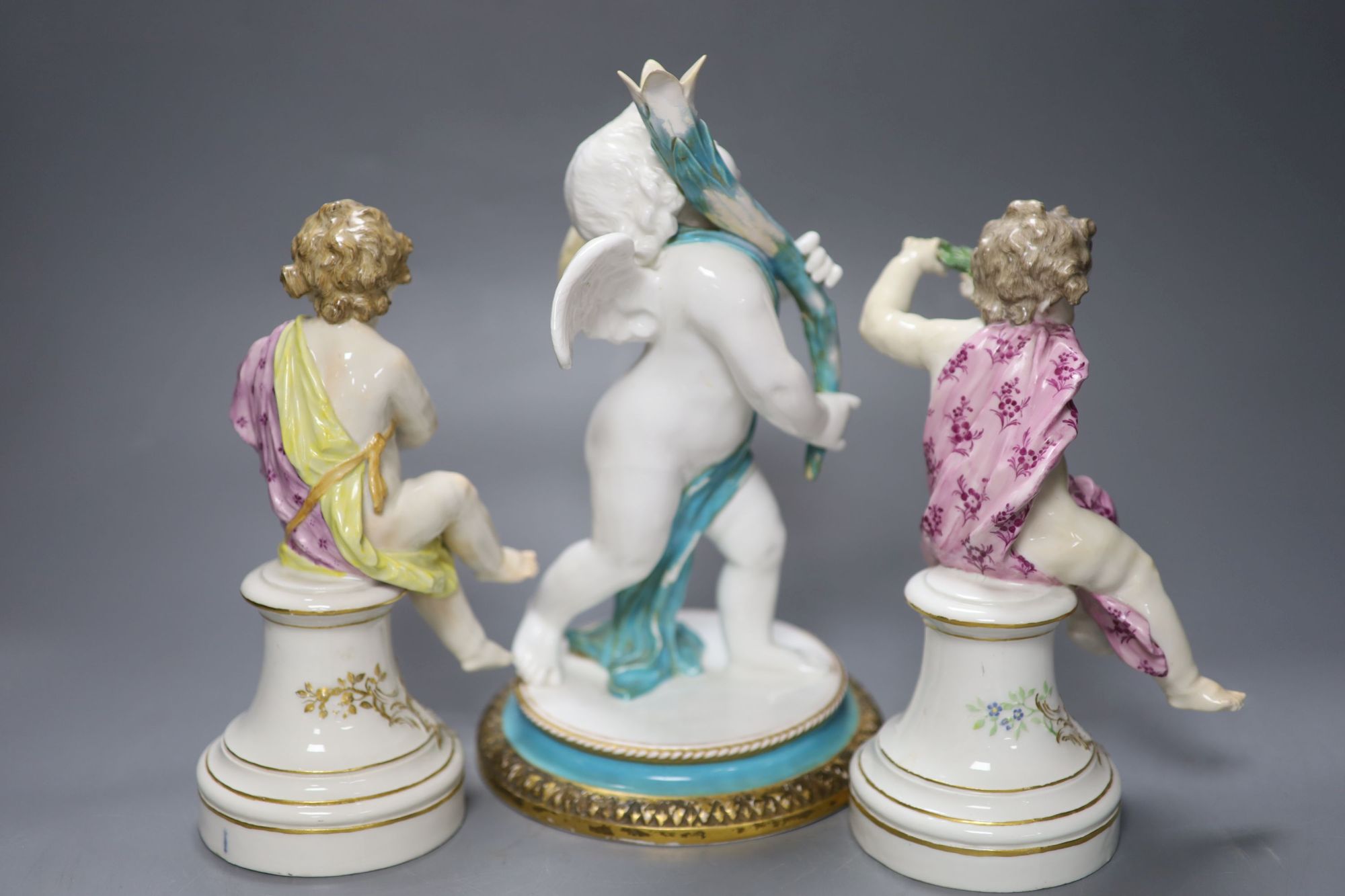 A pair of 19th century Berlin seated cherubs and a Continental porcelain figure of a cherub holding a cornucopia, tallest 27cm